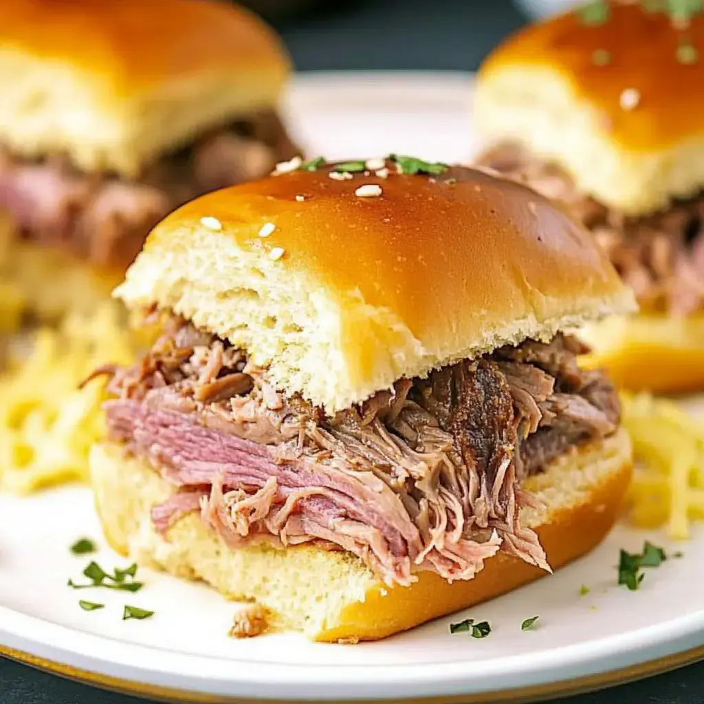 A close-up of a pulled pork sandwich on a soft, glossy bun, garnished with herbs, with additional sandwiches visible in the background.