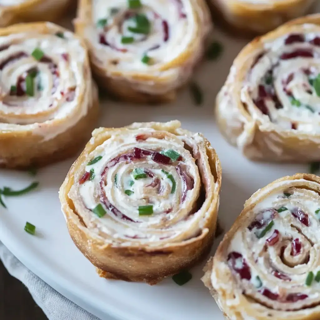 A close-up of spiral-shaped rolls filled with cream cheese and garnished with green onions, arranged on a white plate.