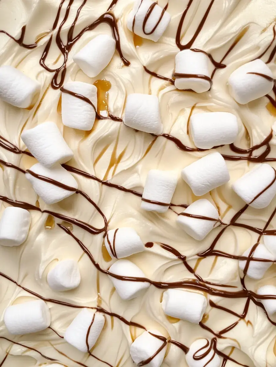 A dessert featuring a creamy base topped with small marshmallows and drizzled with chocolate syrup.