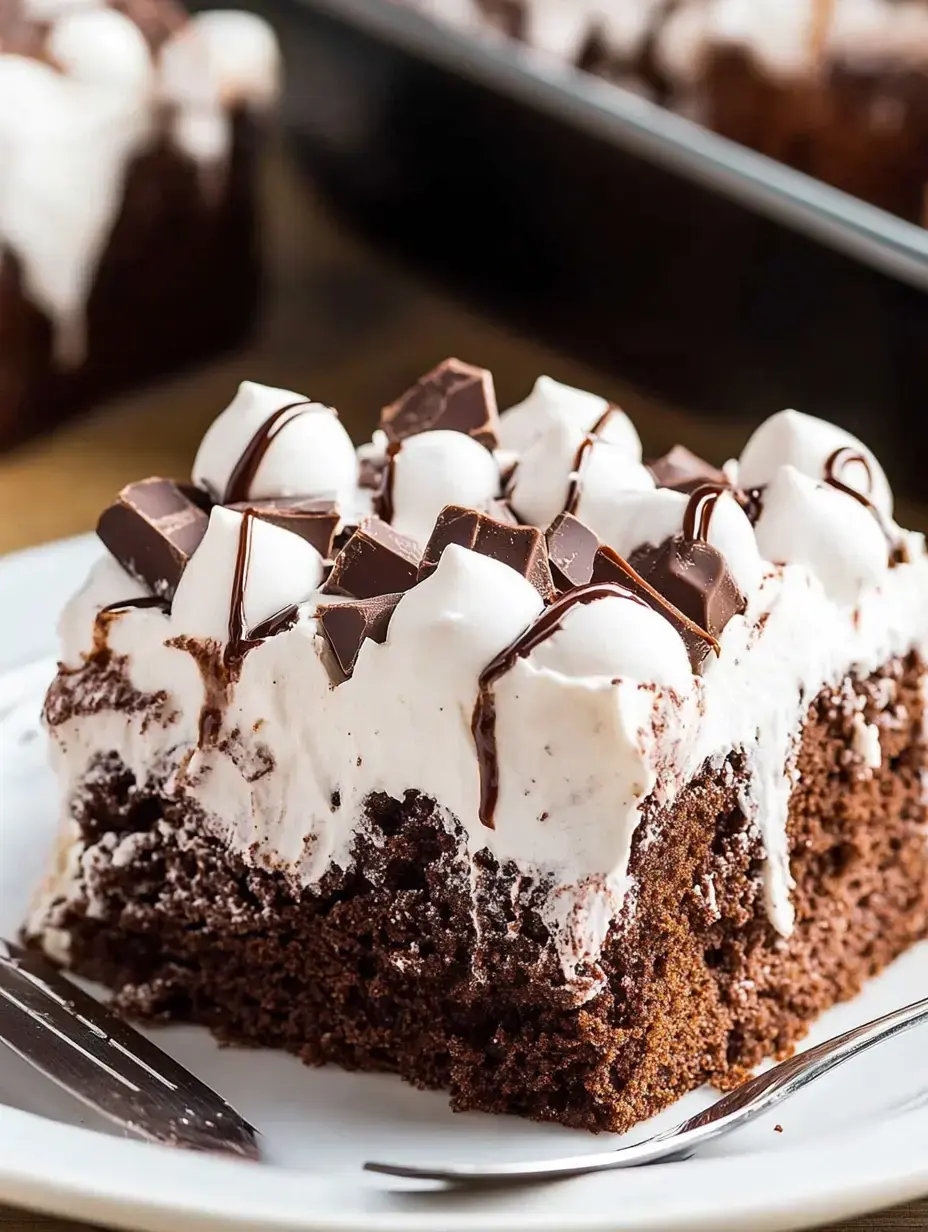 A slice of chocolate cake topped with whipped cream, chocolate chunks, and drizzled with chocolate sauce on a white plate.