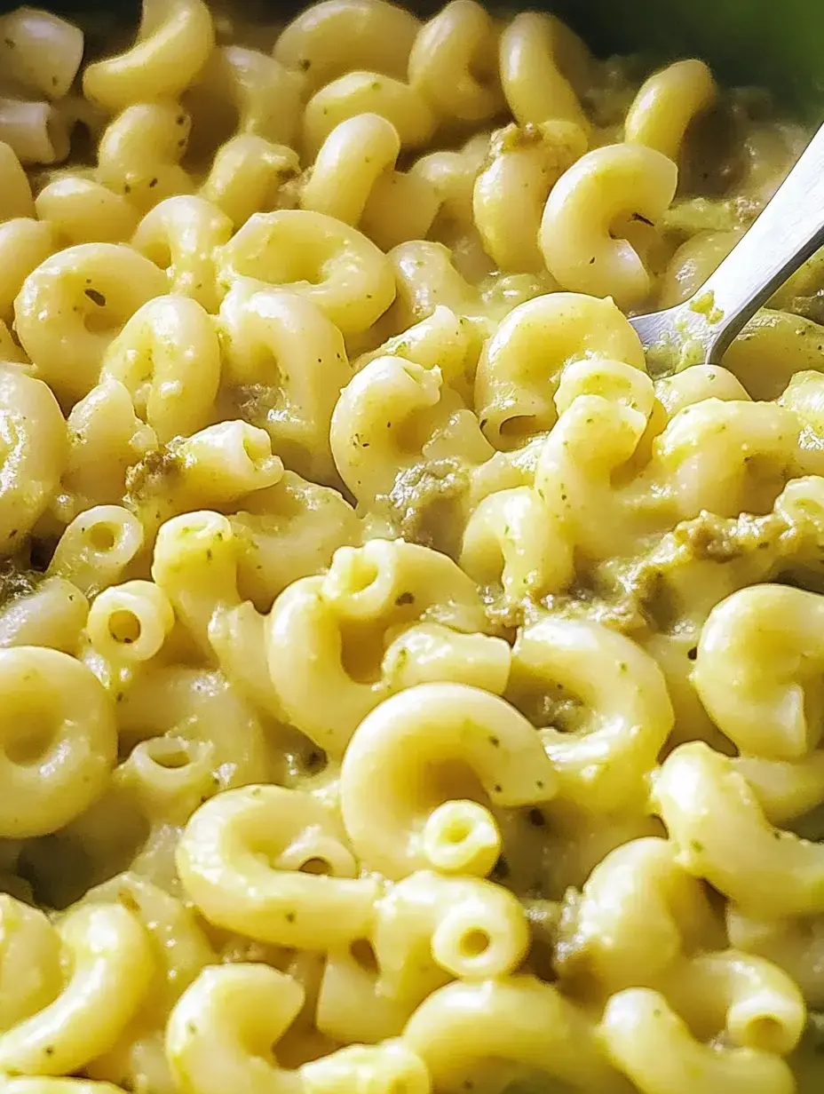 A close-up of creamy macaroni pasta mixed with a yellow-green sauce.