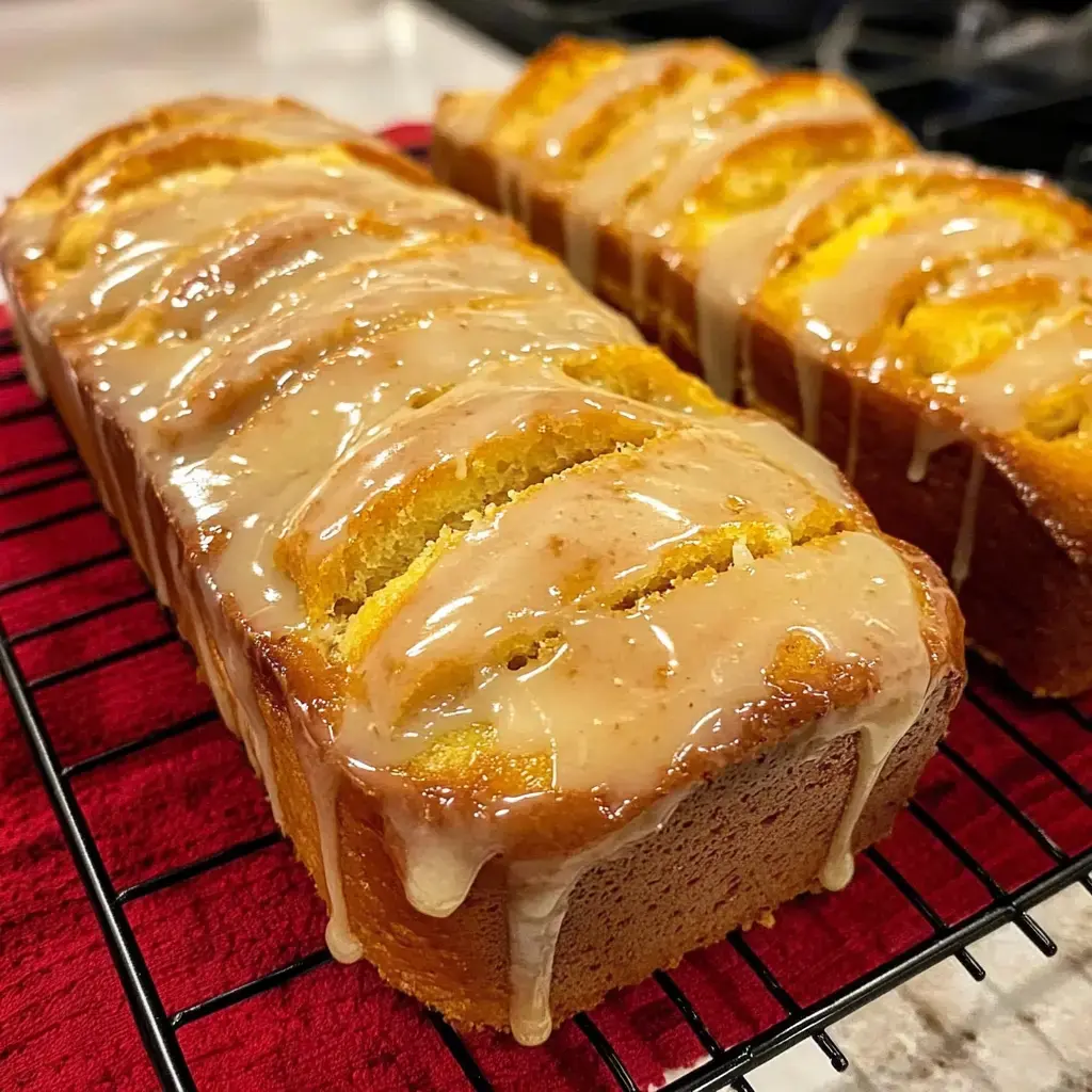 Two loaves of glazed cake cooling on a wire rack.