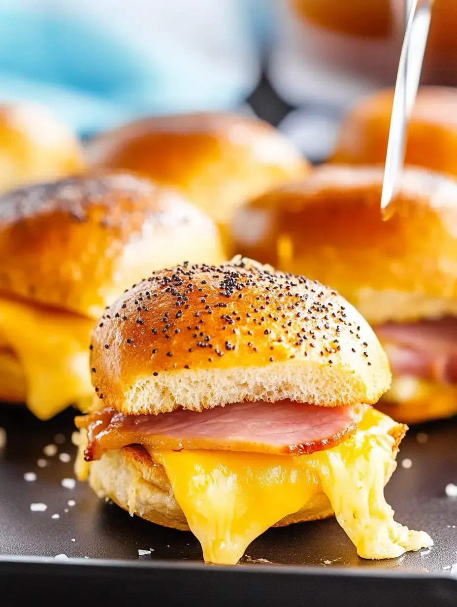 A close-up of a cheesy, ham-filled slider on a soft, golden bun, with melted cheese oozing from the sides.