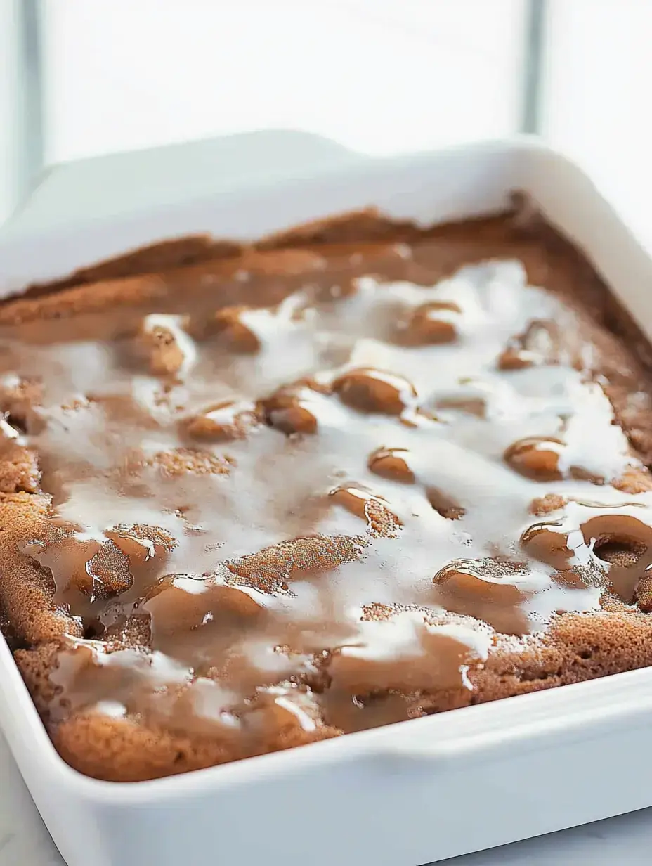 A freshly baked chocolate cake topped with a glossy caramel glaze in a white dish.