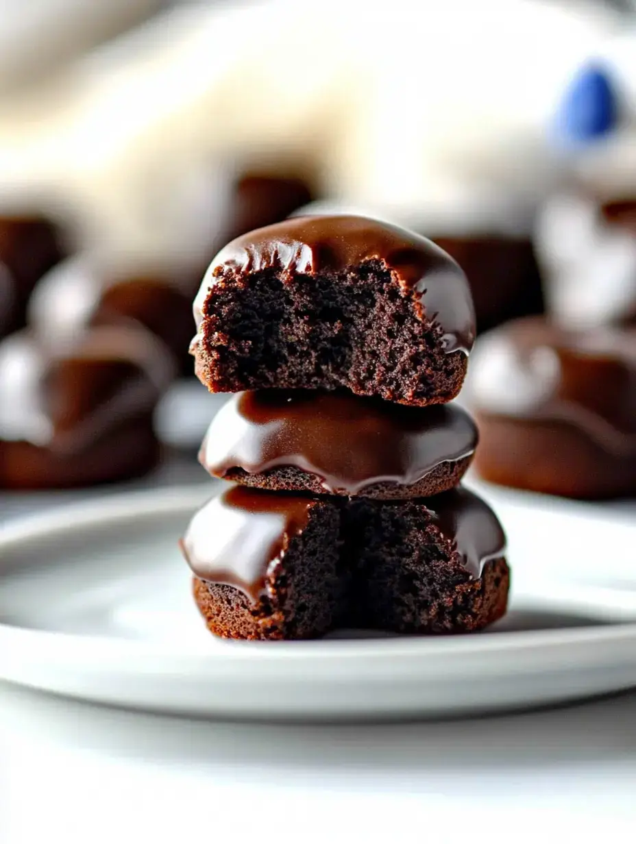 A stack of three chocolate-covered cakes, with the top two showing a bite taken out, revealing a moist chocolate interior.