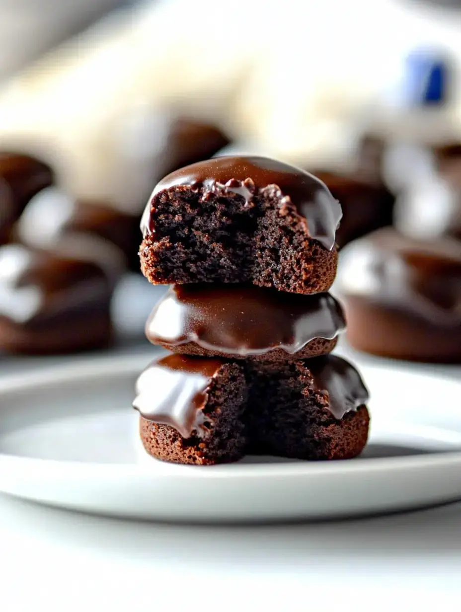 A stack of three chocolate-coated cake bites, with one partially bitten to reveal a soft, textured interior.