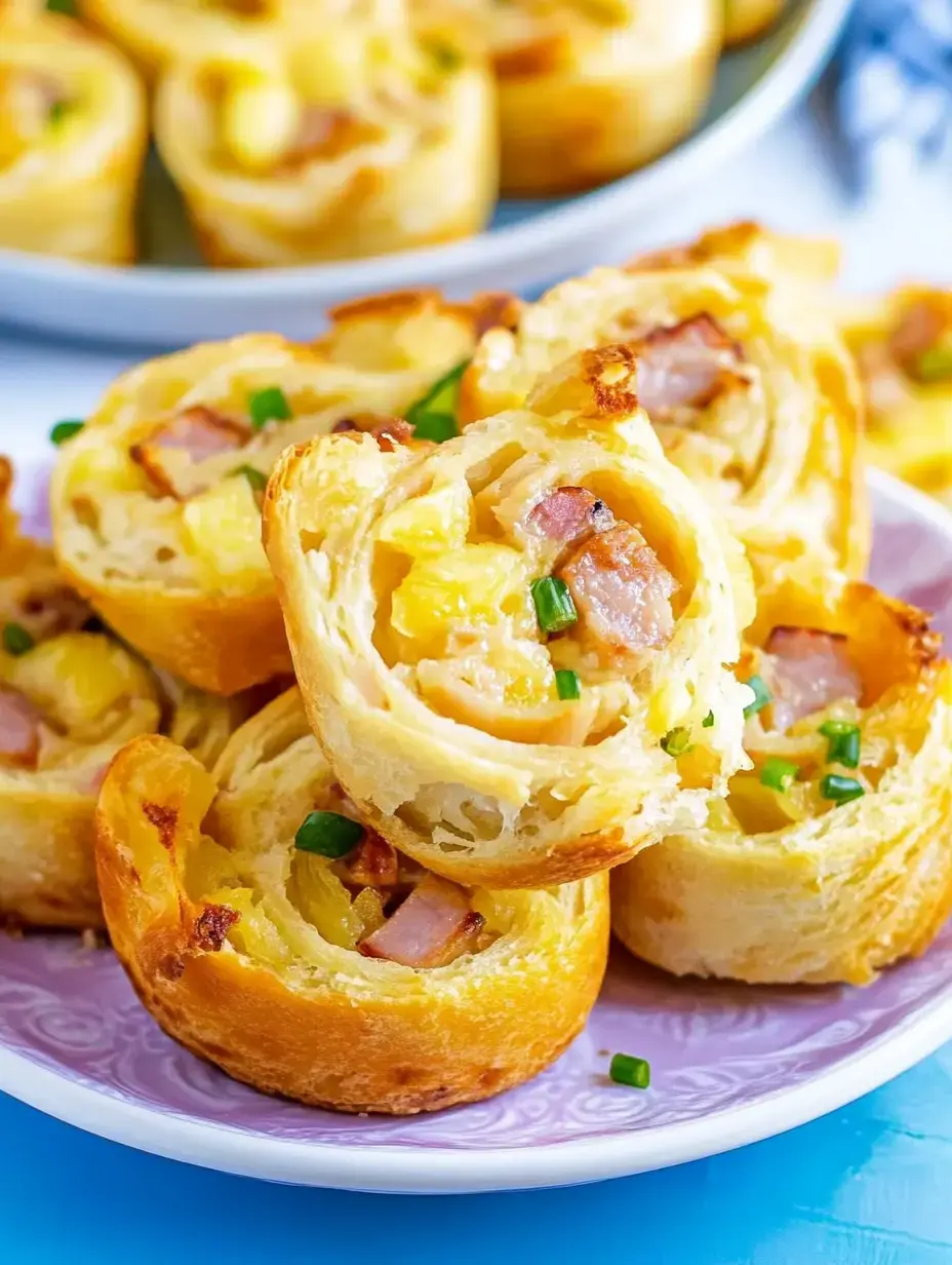 A close-up of golden, flaky pastry rolls filled with ham, pineapple, and chopped green onions, displayed on a plate.