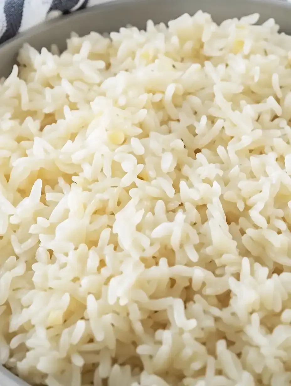 A close-up of fluffy, cooked white rice in a gray bowl.