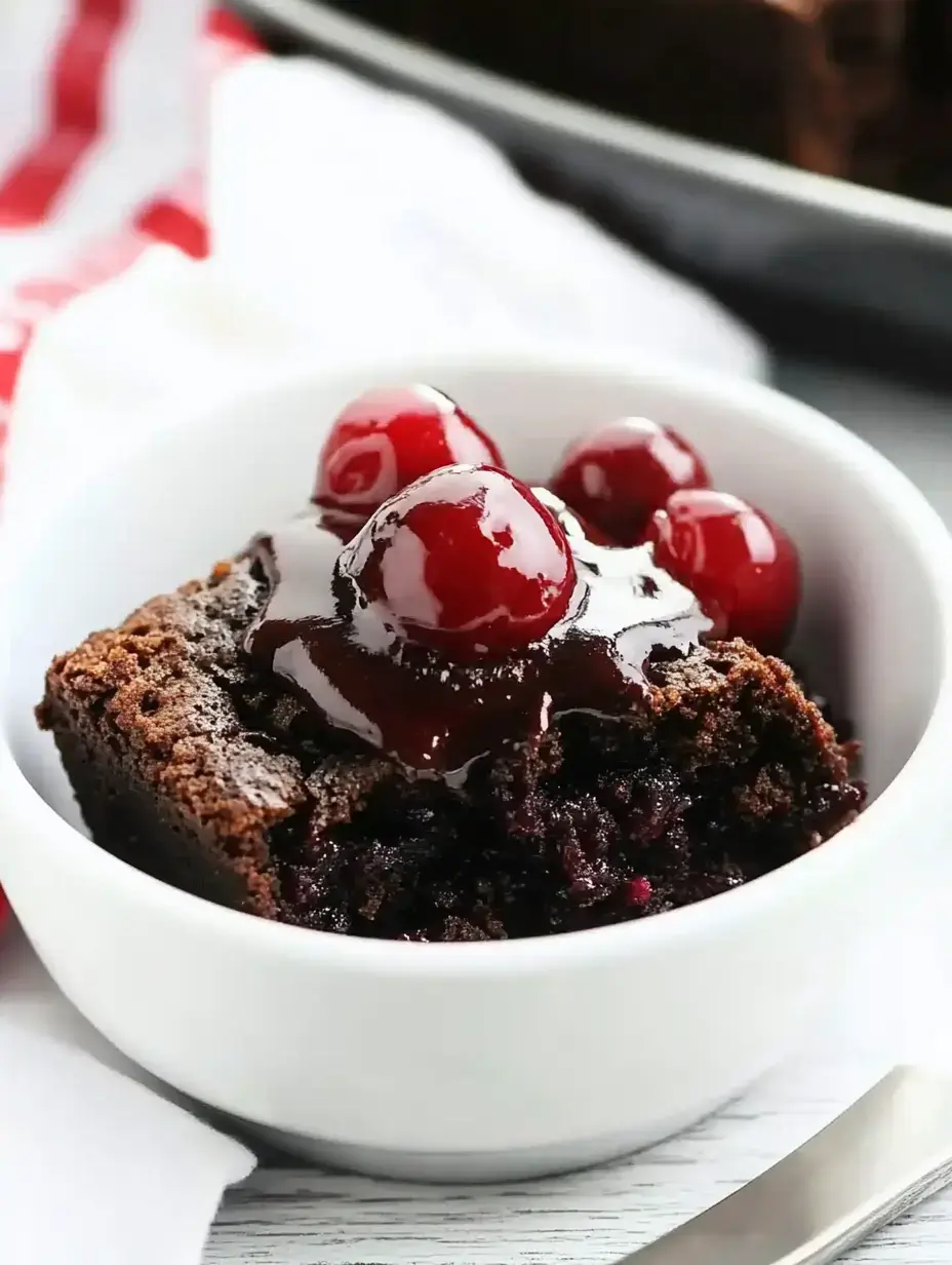 A close-up of a chocolate dessert topped with cherries and chocolate sauce in a white bowl.