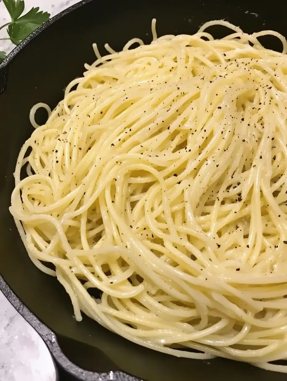 A close-up of creamy, black pepper spaghetti served in a cast iron skillet.