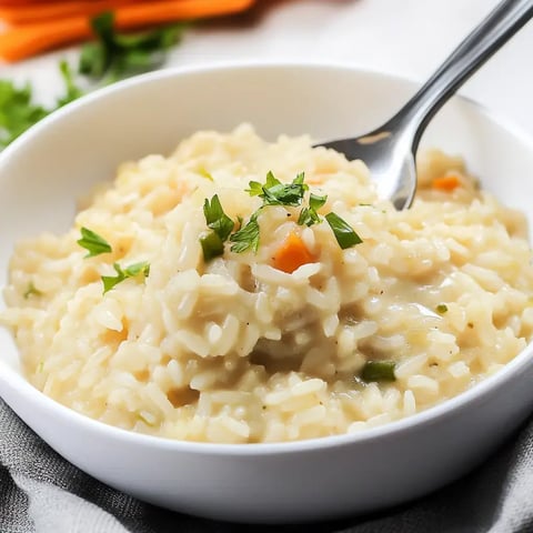 A bowl of creamy risotto garnished with fresh parsley and colorful vegetables.